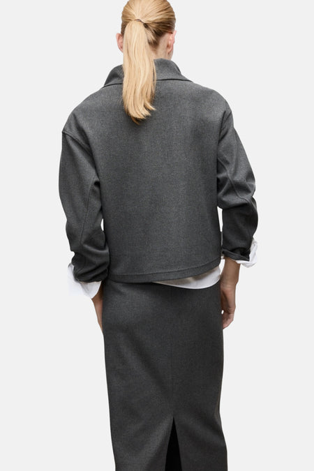 Grijze dameskleding, rok en blazer, achterkant gezien.
