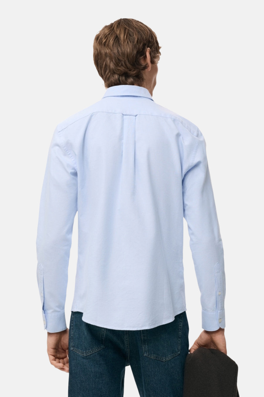 Achterkant van een man in een lichtblauw overhemd en spijkerbroek.