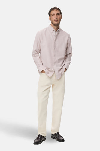 Man in roze overhemd, crèmekleurige broek en leren loafers.