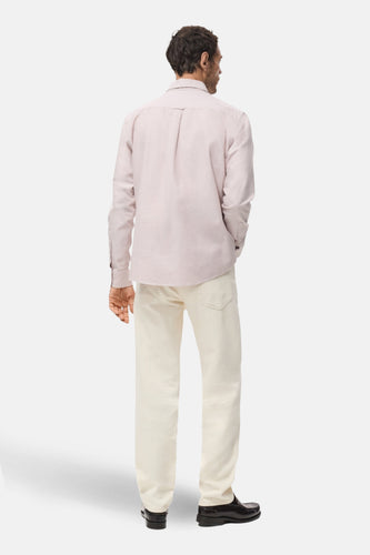 Man van achteren in een roze overhemd en beige jeans, met zwarte schoenen.