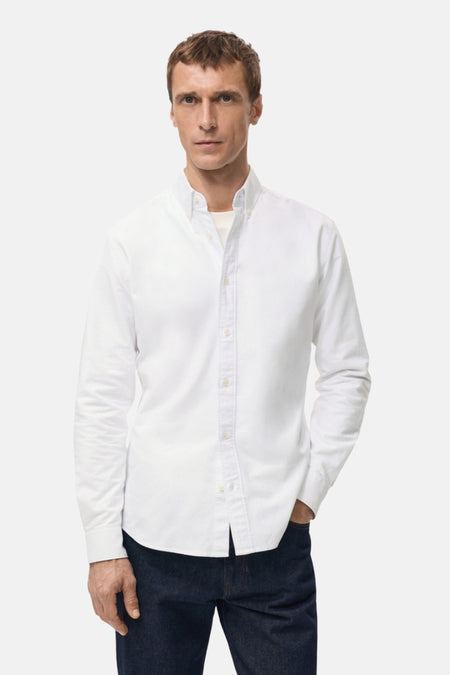 Man met wit overhemd en donkere jeans.
