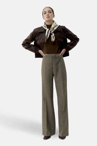Pantalon multicolore de MANGO, avec un motif pied-de-poule et des jambes larges, porté avec une veste brune et un foulard en soie.