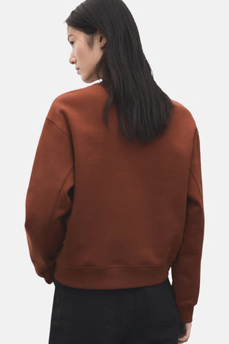 Bruine sweater met ronde hals van MANGO, gezien vanaf de achterkant, gecombineerd met een zwarte broek.