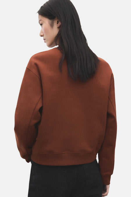 Bruine trui, zwarte broek.
