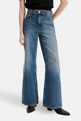 Jean en denim bleu, de MANGO, avec une coupe droite et une ceinture noire avec des anneaux argentés.