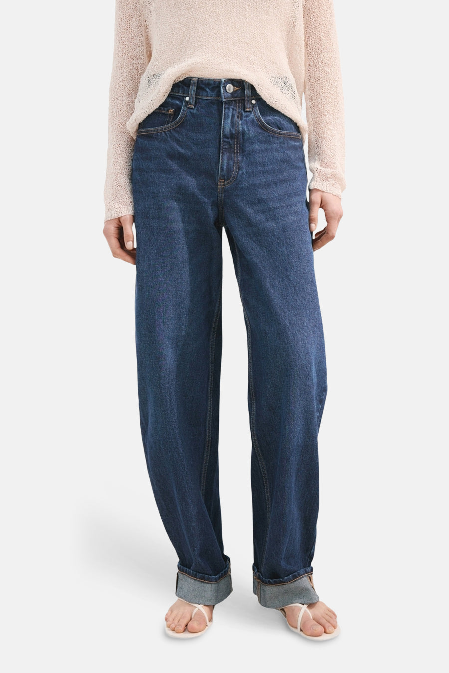 Jean en denim bleu marine coupe spéciale de MANGO, avec des jambes retroussées et associé à un pull en maille lâche.