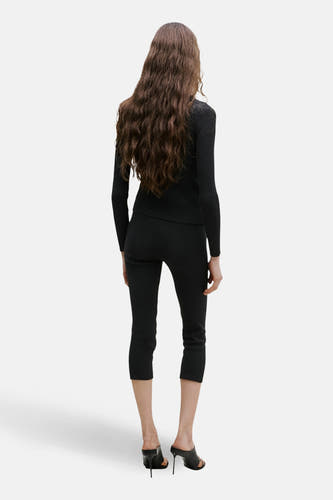 Zwart gilet van MANGO, rugzijde, gecombineerd met een zwarte broek en open hakken.