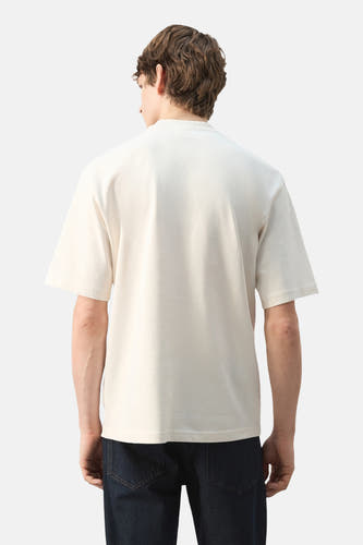 Ecru T-shirt met korte mouwen van MANGO, gezien van achteren, gedragen met donkere jeans.