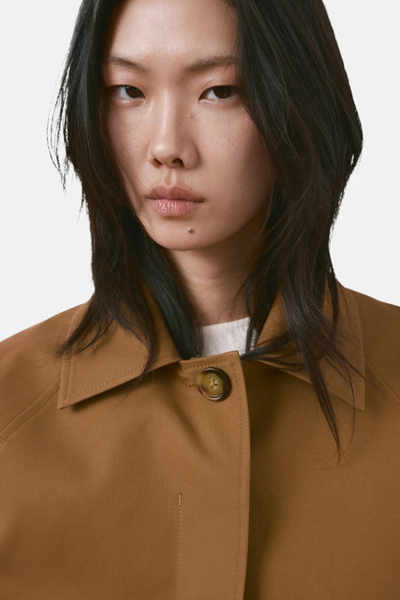Manteau court marron de MANGO, à manches longues et avec un col, sur fond blanc.