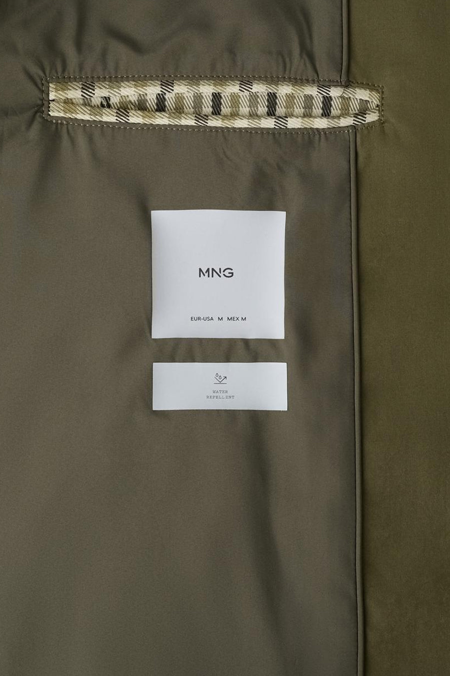 Veste courte marron de MANGO, avec une étiquette et un détail à carreaux écossais à l'intérieur.