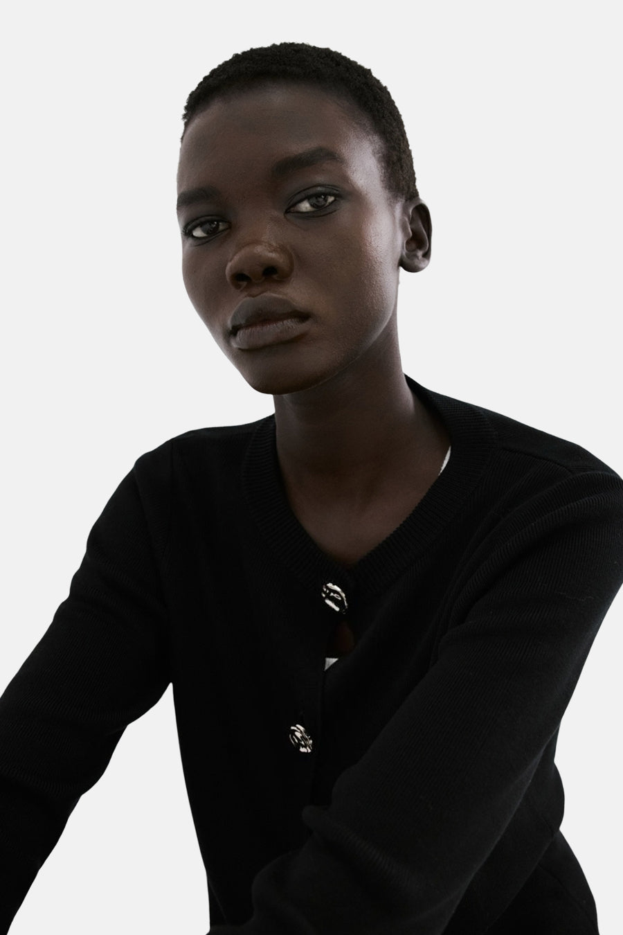 Gilet noir de MANGO, avec boutons argentés, porté sur un haut blanc.