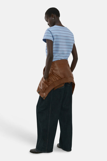Blauw gestreept T-shirt van MANGO, met korte mouwen, gecombineerd met een bruine jas en wijde donkere jeans.