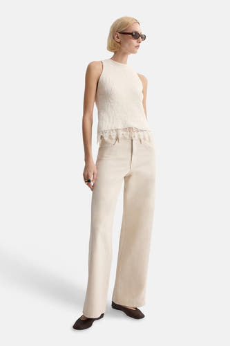Haut écru sans manches de MANGO, fini avec des détails en dentelle, porté avec un jean beige ample et des chaussures marron.