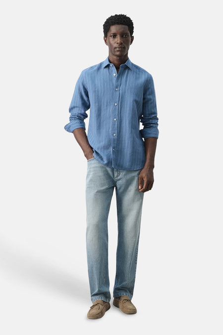 Chemise bleue à manches longues et à rayures verticales de MANGO, portée avec un jean et des mocassins.