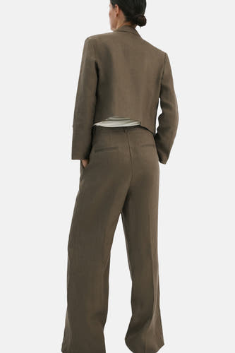 Khaki broek van MANGO met wijde pijpen en achterzakken, gedragen door een model met een korte blazer.