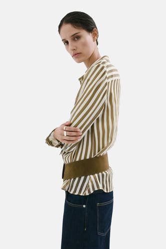 Chemise rayée blanche et vert olive de MANGO, stylisée avec une large ceinture marron et un jean foncé.