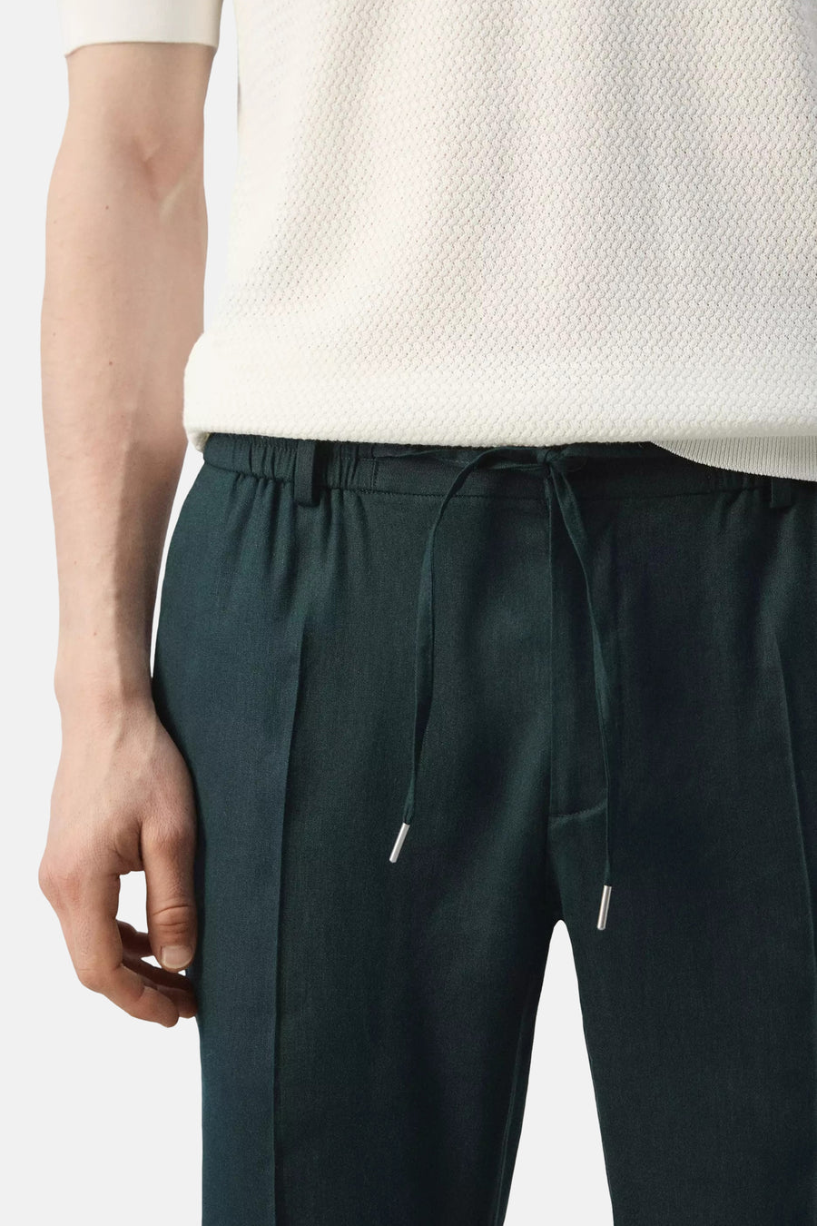 Pantalon vert MANGO avec taille à cordon de serrage, embouts argentés et porté avec un t-shirt blanc texturé.