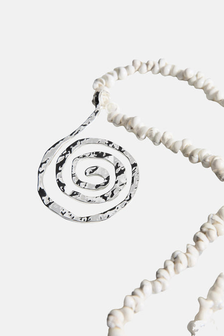 Collier court blanc et argenté de MANGO avec pendentif spiralé martelé et coquillages.