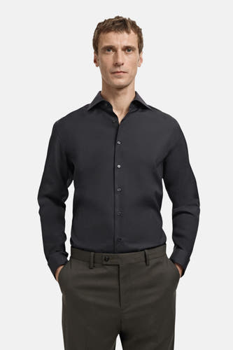 Chemise noire à manches longues de MANGO, vue de dos, associée à un pantalon foncé.