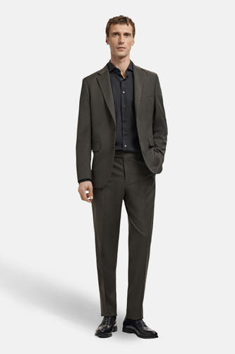Chemise noire à manches longues de MANGO, portée sous un manteau gris-brun avec un pantalon et des chaussures noires.