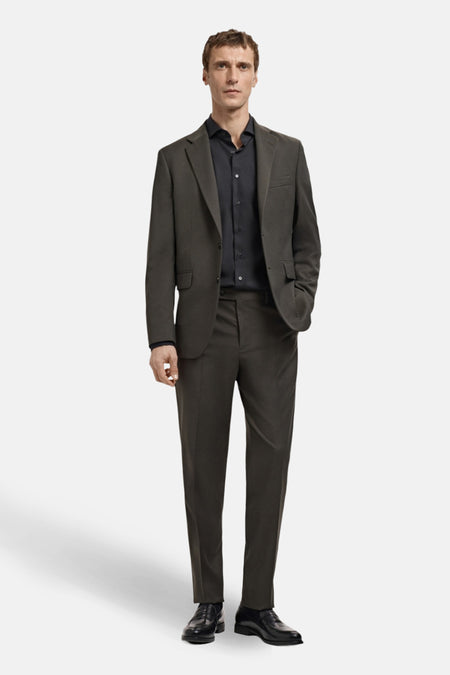 Man in grijsbruin pak met zwart overhemd en schoenen.