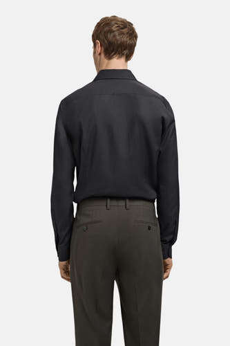 Zwart overhemd met lange mouwen van MANGO, gezien vanaf de achterkant, gecombineerd met een donkere pantalon.
