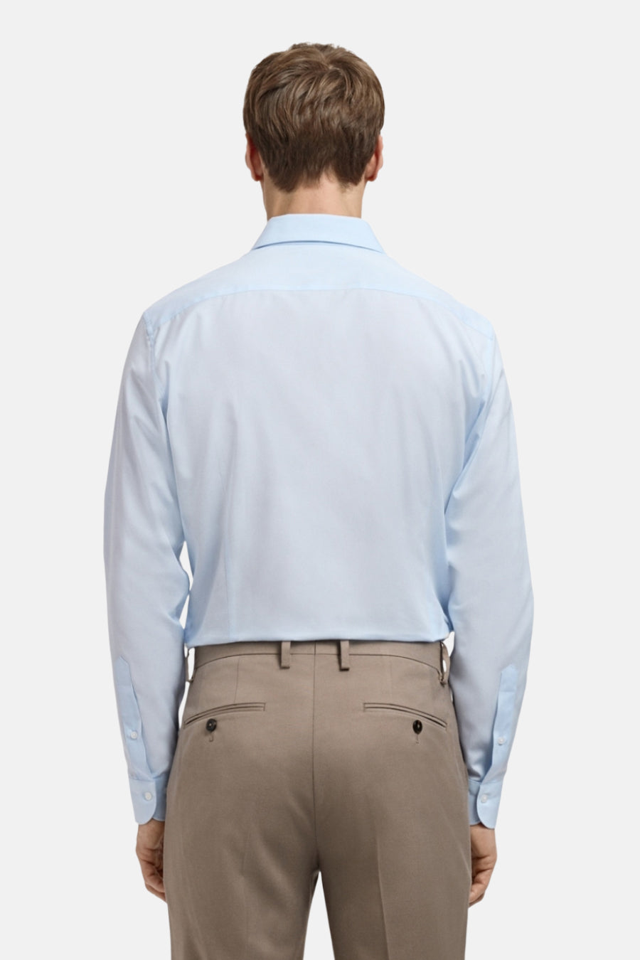 Achterkant van een man in een lichtblauw overhemd en beige broek.