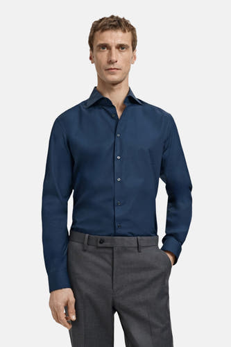 Chemise bleue à manches longues de MANGO, vue de derrière, associée à un pantalon gris.