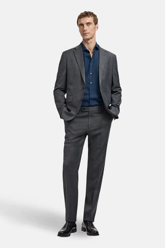 Chemise bleue à manches longues de MANGO portée sous un manteau gris avec des chaussures noires.