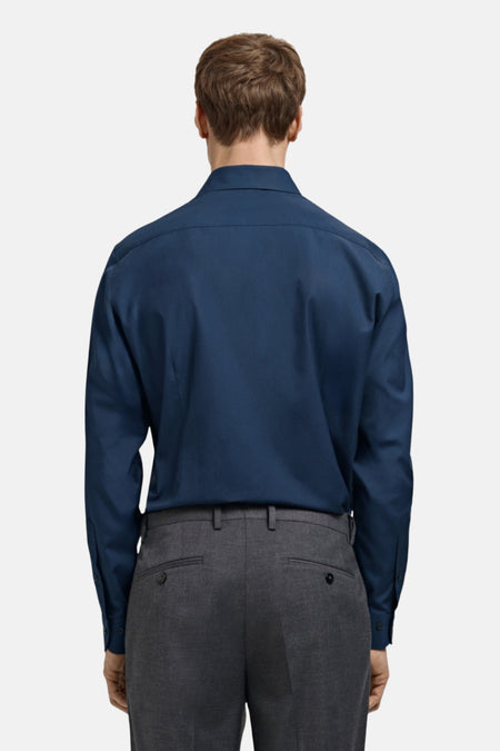 Man in blauw overhemd en grijze pantalon, achterkant.
