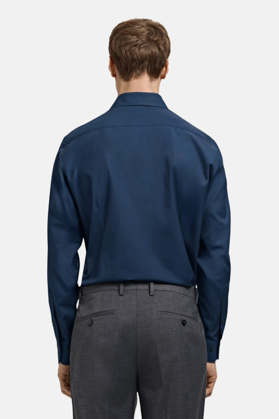 Man in blauw overhemd en grijze pantalon, achterkant.