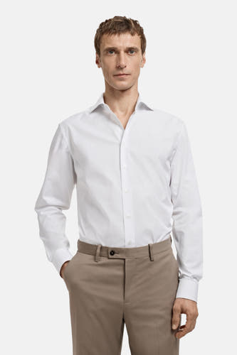 Blouse blanche à manches longues de MANGO, vue de derrière, associée à un pantalon marron.