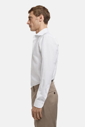 Chemise blanche à manches longues de MANGO, avec un pantalon beige, en vue latérale.