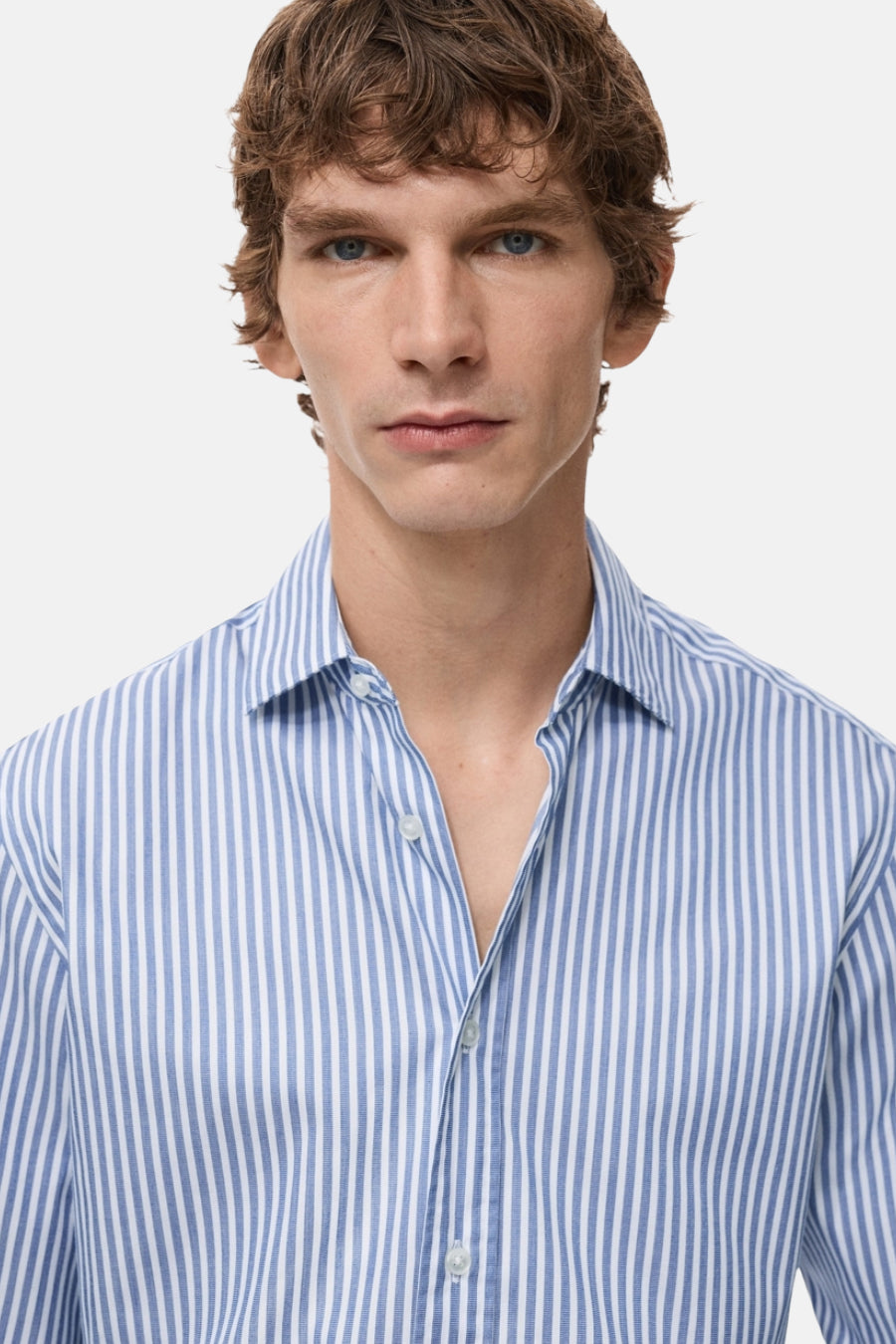 Chemise bleue rayée avec manches longues de MANGO, portée par un homme aux cheveux bruns.