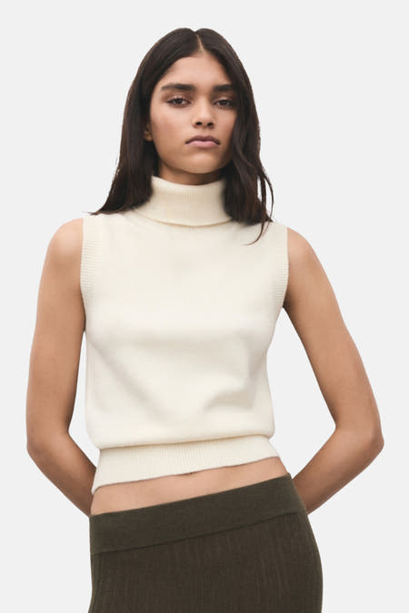 T-shirt écru de MANGO, avec une jupe verte à manches longues et un bracelet en bois.