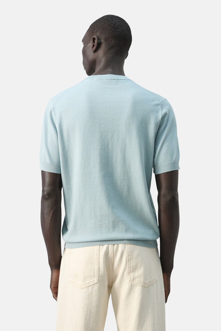 Blauw T-shirt met korte mouwen van MANGO, gezien van achteren, gecombineerd met een lichtkleurige broek.
