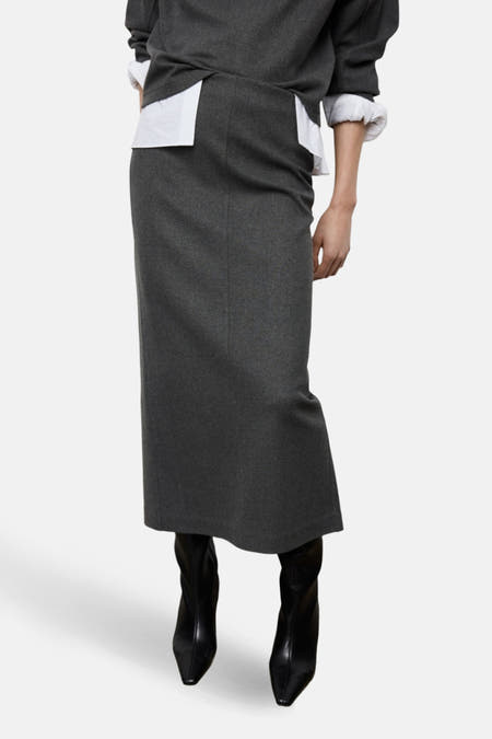 Long manteau gris de MANGO, avec une fente à l'arrière et associé à un blazer gris.