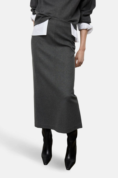 Grijze rok, witte blouse, zwarte laarzen.