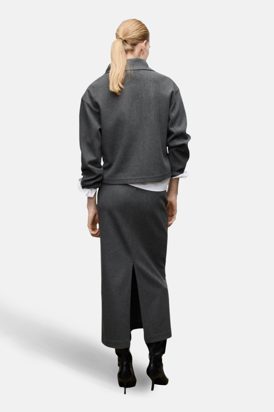 Lange grijze rok van MANGO, met split aan de achterkant en gecombineerd met een grijze blazer.