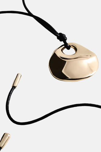 Collier court doré de MANGO, avec un pendentif de forme organique sur un cordon noir avec des accents dorés.