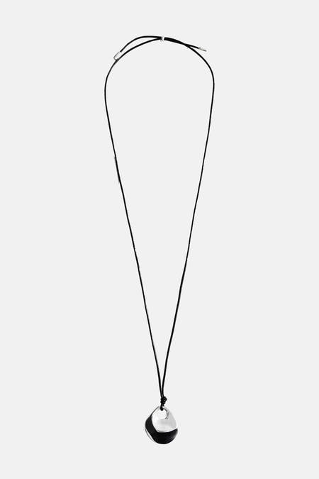 Korte zilveren halsketting van MANGO, met een zwarte koord en een asymmetrische hanger.
