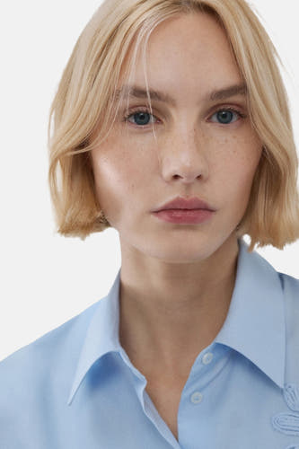 Chemise bleue à manches longues de MANGO, gros plan sur un mannequin avec un carré blond et des yeux bleus.
