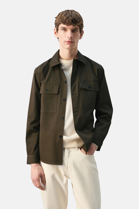 Chemise kaki à manches longues de MANGO, vue de dos, associée à un pantalon de couleur crème.