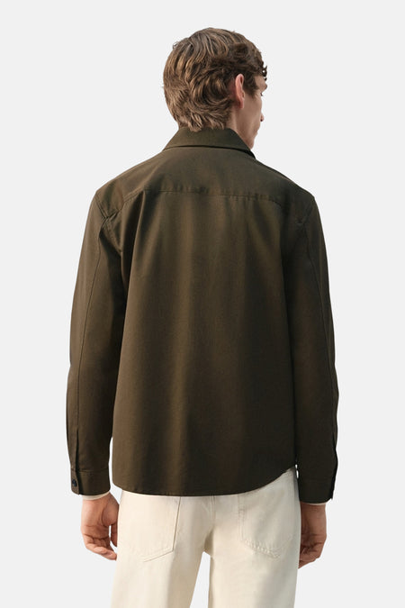 Kaki overhemd met lange mouwen van MANGO, gezien van achteren, gecombineerd met een crèmekleurige broek.
