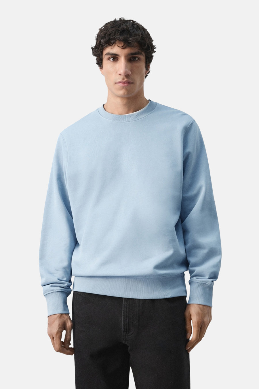 Pull bleu à col rond de MANGO, vu de dos, combiné avec un pantalon noir.