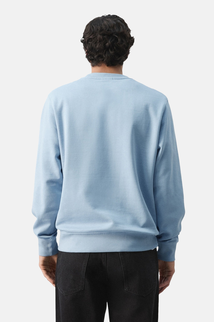 Blauwe sweater met ronde hals van MANGO, gezien van achteren, gecombineerd met een zwarte broek.
