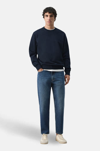 Pull noir à col rond de MANGO, porté avec un jean et des chaussures crème.