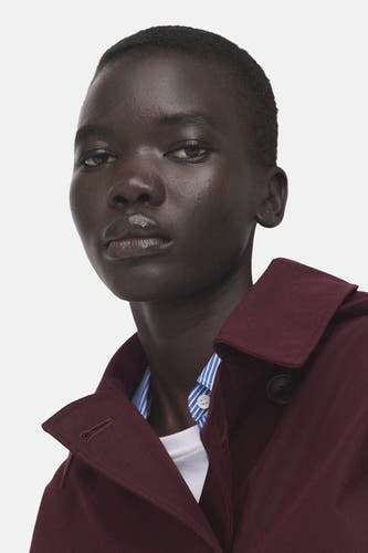 Veste courte bordeaux de MANGO, avec fermeture à boutons et une chemise rayée bleu et blanc en dessous.