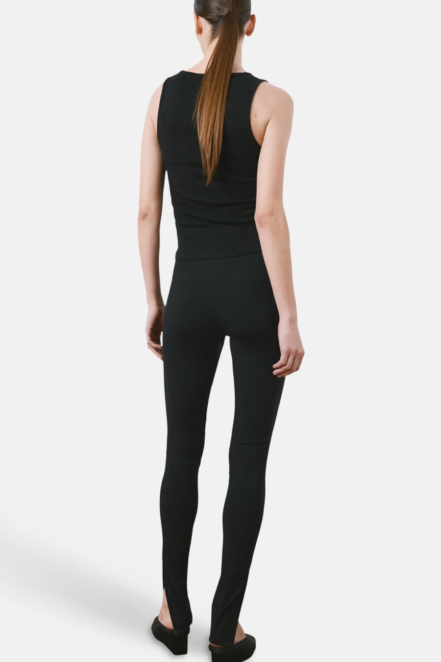 Zwarte tanktop van MANGO, getoond van achteren met een paardenstaart en zwarte legging met split aan de zoom.
