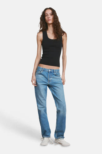 Haut noire de MANGO, avec une texture côtelée et combinée avec un jean bleu et des baskets blanches.
